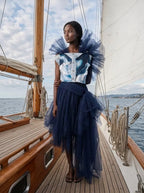 Woman wearing sustainable Shoredarling Denim Organza Chiffon Dress on a boat by the seashore