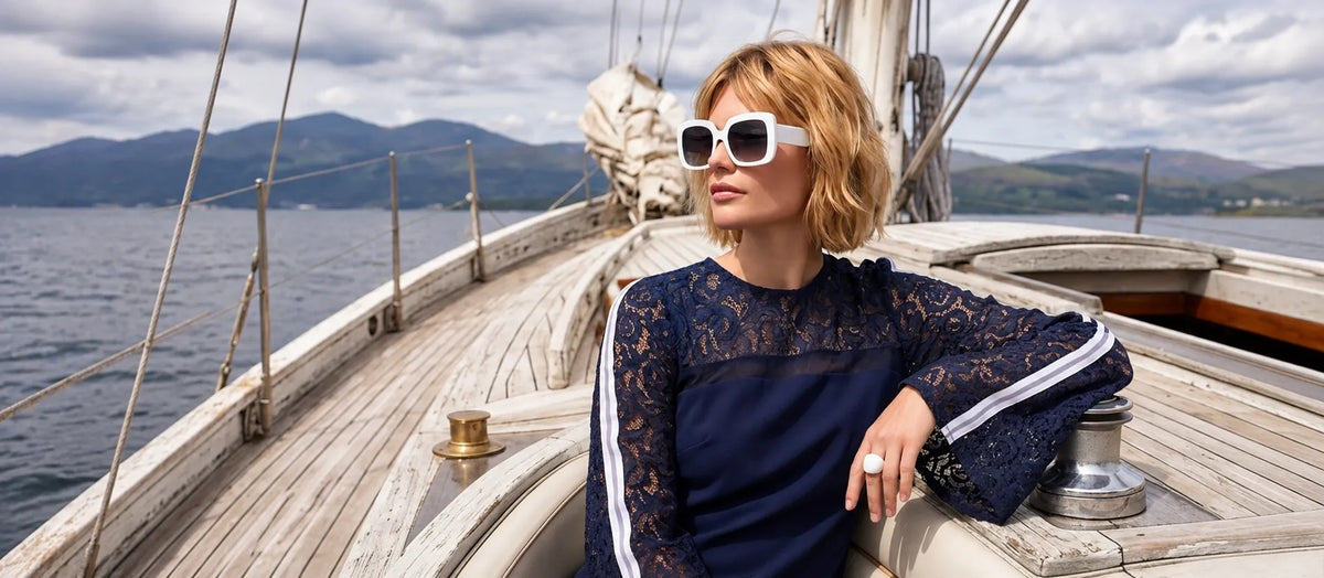 Woman wearing sustainable  Shoredarling Luxe Lace-Trim Bell Sleeve Dress on a boat by the seashore